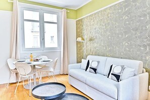 A dining area with a round table, chairs, and a sofa. - Charming apartment in Neuilly-sur-Seine (Neuilly-sur-Seine)