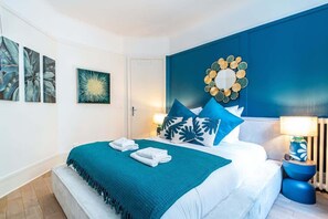Ein Hotelzimmer mit Bett, blauer Wand und dekorativem Spiegel.