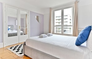A bedroom with a bed, a mirror, a window, and a door. - Superb 2-bedroom apartment in Neuilly-sur-Seine (Neuilly-sur-Seine)