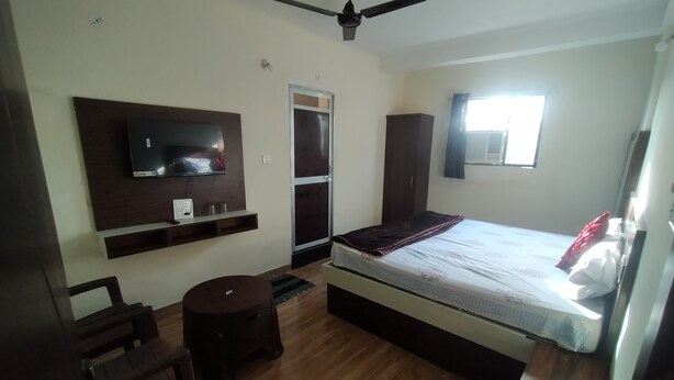Une chambre à coucher avec un lit, un téléviseur fixé au mur, une armoire et un ventilateur de plafond.