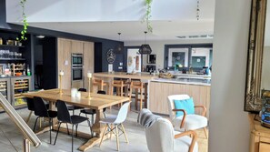 Een moderne keuken met houten kastjes, een centraal eiland en een eethoek met een houten tafel en stoelen.