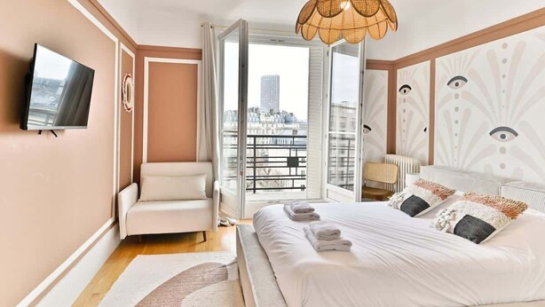 Een moderne hotelkamer met een bed, een televisie, een bank en een balkon met uitzicht over de stad.