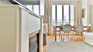 Een moderne hotelkamer met een eethoek, grote ramen en uitzicht op de stad.