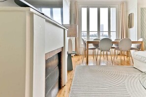 A modern hotel room with a dining area, large windows, and a view of the city. - Beautiful apartment with unobstructed views in Neuilly (Neuilly-sur-Seine)