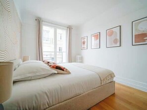 A bedroom with a bed, a window with curtains, and framed pictures on the wall. - An intimate and bright haven in Neuilly (Neuilly-sur-Seine)