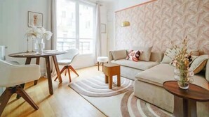 A modern living room with a sofa, a small round table, and a dining table with chairs. - An intimate and bright haven in Neuilly (Neuilly-sur-Seine)