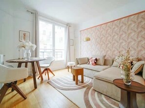 A modern living room with a sofa, a small round table, and a dining table with chairs. - An intimate and bright haven in Neuilly (Neuilly-sur-Seine)