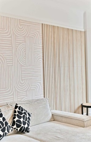A modern living room with a sofa, two patterned cushions, and a vertical wooden panel. - Neuilly-sur-Seine, family cocoon (Neuilly-sur-Seine)