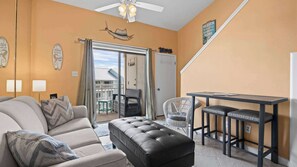 Ein Wohnzimmer mit einer Couch, Hocker und einem Essbereich mit Tisch und Stühlen.