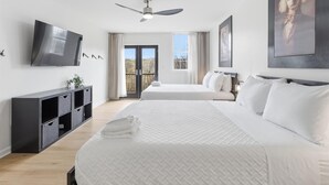 A hotel room with two beds, a TV, a ceiling fan, and a balcony with a view. - Amazing 5BR Retreat Near Downtown Indy (Indianapolis)