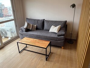 A modern living room with a grey sofa, two pillows, a wooden coffee table, and a floor lamp. - Tranquil 1-bedroom studio with AC in Mar del Plata (Mar del Plata)