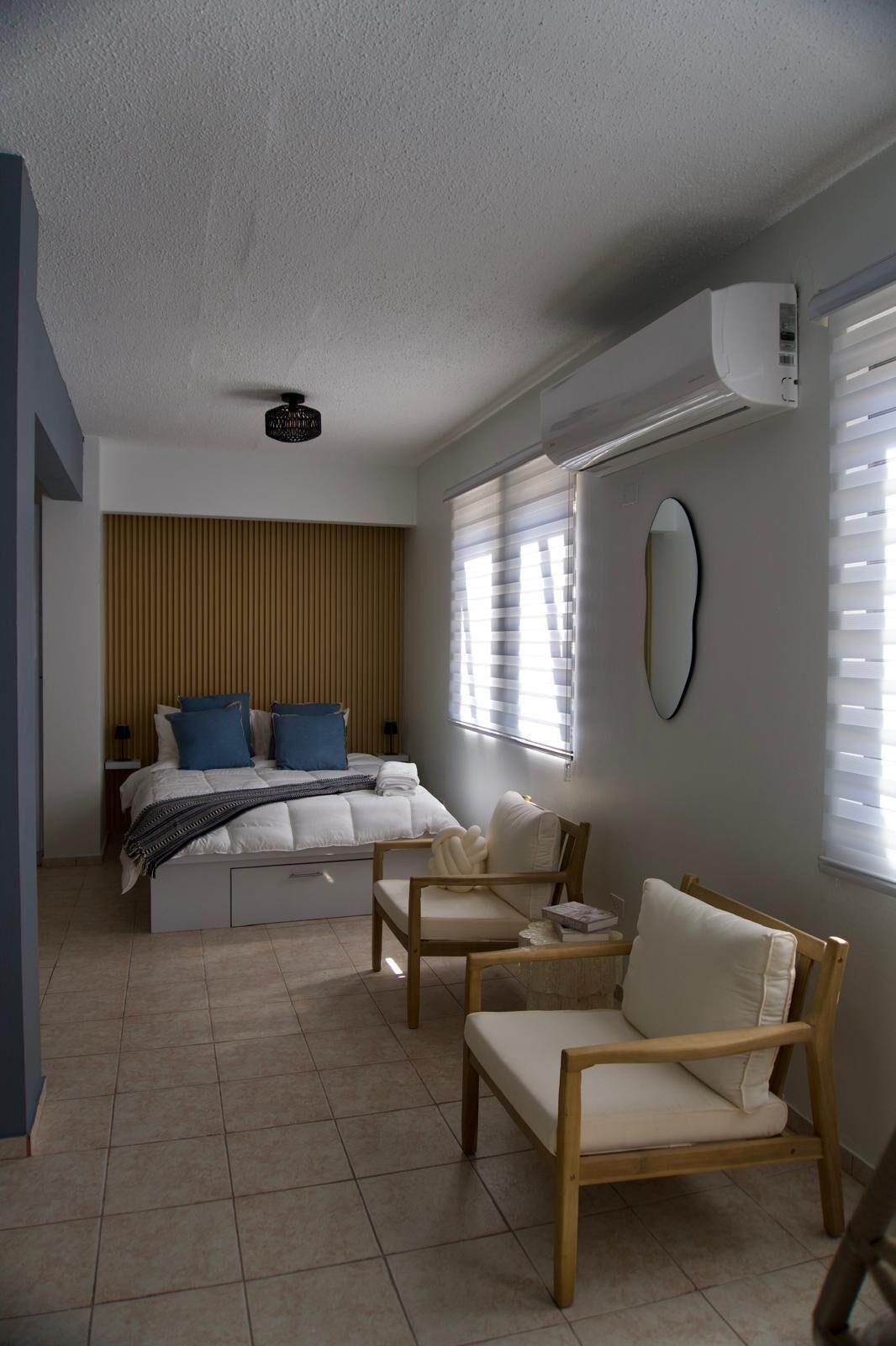 Una camera da letto con un letto, comodini, una sedia, un tavolino e una finestra con persiane.