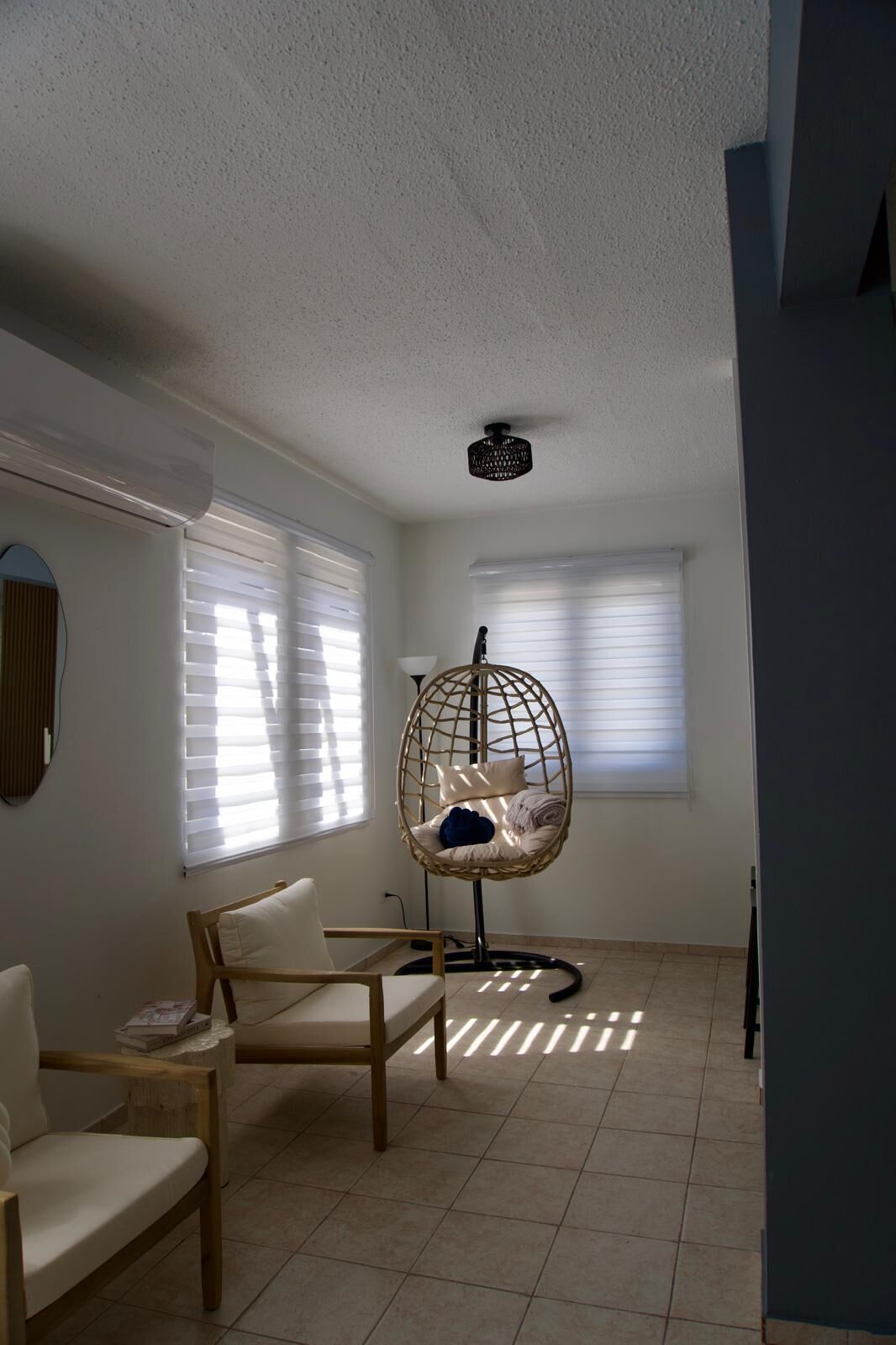 A room with a hanging chair, a wooden table, and a ceiling projector.