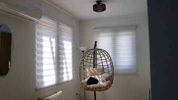 A room with a hanging chair, a wooden table, and a ceiling projector.