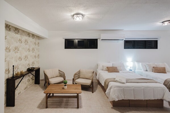 Un dormitorio con cama, dos sillas, una mesa y un equipo de aire acondicionado.