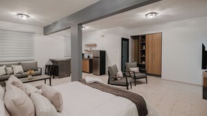 A modern hotel room with a large bed, a sofa, a dining area, and a TV. - 623 Boquerón Villas (Boquerón)