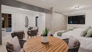A modern room with a bed, a round wooden table, wicker chairs, and a potted plant. - 623 Boquerón Villas (Boquerón)