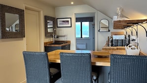 A modern kitchen with a wooden island, bar stools, and a view of the living area.