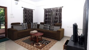 Una sala de estar con un sofá marrón, cojines estampados, una mesita de centro y un televisor.