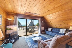 Ein Holzinterieur mit Fernseher, Sofa und Blick ins Freie.