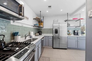 A modern kitchen with stainless steel appliances, a gas stove, and a refrigerator. - Juniper Presents: Private Pool, Hot Tub, Golf Carts and Lake Access (Grand Beach)
