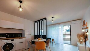 Eine moderne Küche mit Waschmaschine, Essbereich mit Stühlen und einem großen Fenster mit Vorhängen.