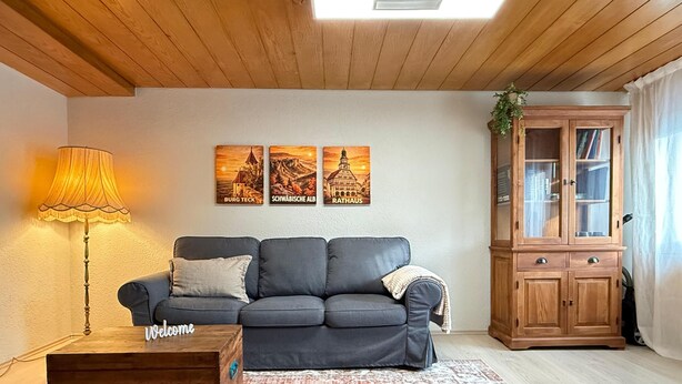 A living room with a grey sofa, a wooden coffee table, a lamp, and a cabinet with glass doors. - Casa Lindach - A cozy temporary home (Kirchheim unter Teck)