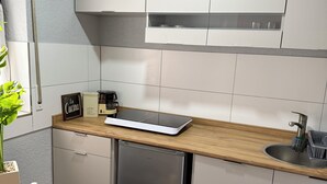 A modern kitchen with white cabinets, a wooden countertop, a built-in dishwasher, and a coffee machine. - Casa Lindach - A cozy temporary home (Kirchheim unter Teck)