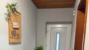 A hallway with a wooden door, a radiator, a small wooden shelf with a sign, and a plant. - Casa Lindach - A cozy temporary home (Kirchheim unter Teck)