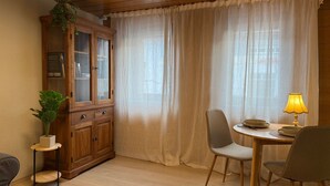 A room with a wooden cabinet, a dining table with chairs, a lamp, and a potted plant. - Casa Lindach - A cozy temporary home (Kirchheim unter Teck)
