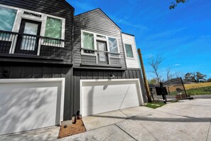 Ein zweistöckiges Haus mit Garage, Balkon und umzäunter Garten.