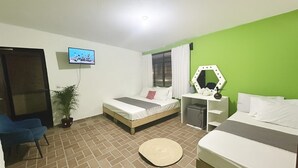 A hotel room with two beds, a TV, a desk with a mirror, a potted plant, and a window with curtains.