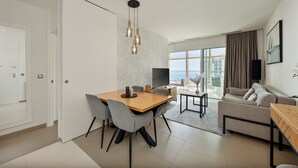 Ein modernes Hotelzimmer mit Essbereich, einer Couch und einem großen Fenster mit Blick auf die Stadt.