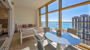Ein geräumiger Balkon mit Meer- und Stadtblick, ausgestattet mit einer Sitzecke, Stühlen und einem Tisch.