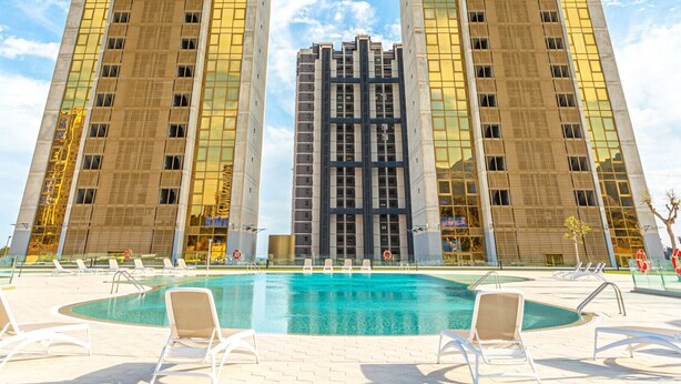 Ein Hochhaus-Hotel mit einem zentralen Atrium und einem Schwimmbeckenbereich mit Liegestühlen.