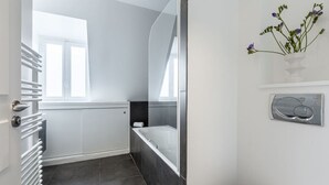Ein modernes Badezimmer mit Badewanne, Toilette und Fenster.