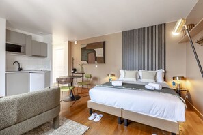 A modern hotel room with a bed, bedside tables, a desk, and a kitchenette. - Arc de Triomphe - 2 personnes - Bail Mobilité (Paris)