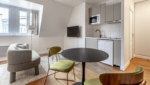 Ein modernes Apartment mit Essbereich, Küchenzeile und einem großen Fenster mit Vorhängen.