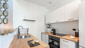 Una cocina moderna con encimera de madera, pileta de acero inoxidable y muebles blancos.