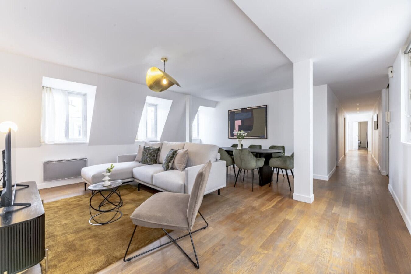 A modern living room with a sofa, a dining table with chairs, and a TV.