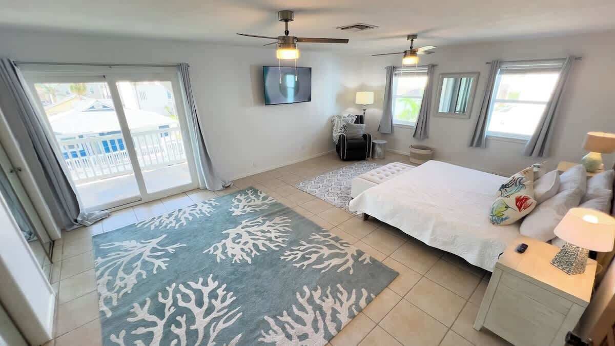 A bedroom with a bed, two nightstands, a desk, a chair, a TV, and a balcony with a view.