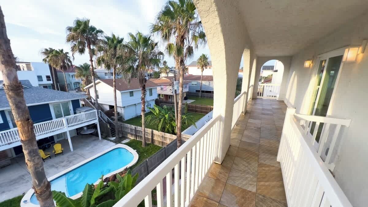 Un balcón con vista a una piscina y casas vecinas.