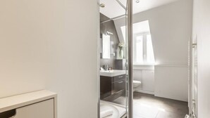 Un bagno moderno con cabina doccia in vetro, un lavabo bianco e un water.