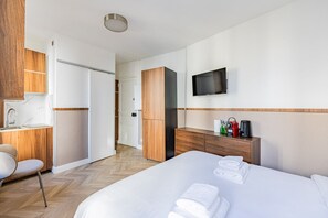A hotel room with a bed, a desk, a chair, a TV, and a minibar. - Montmartre - Métro Guy Moquet - Studio (Paris)