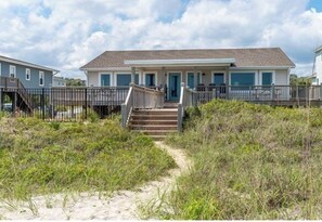 A beachfront house with a wooden deck and stairs leading to the entrance. - Cowabungalow, Oceanfront 6BR 4BA home in Emerald Isle with Private Pool! (Emerald Isle)