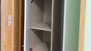 A closet with shelves and hanging space, a door with a 'No Smoking' sign, and a coat rack. - Hostal Retiro (Madrid)