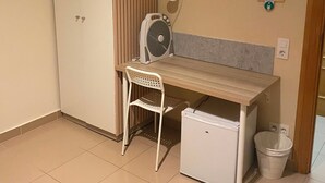 A small room with a desk, chair, and a mini fridge. - Hostal Retiro (Madrid)
