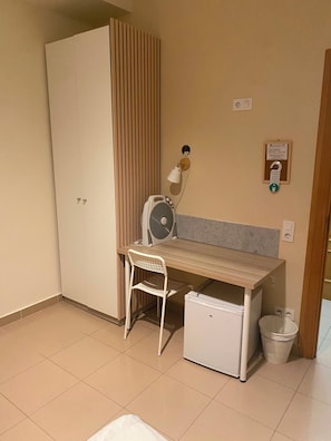 A small room with a desk, chair, and a mini fridge. - Hostal Retiro (Madrid)