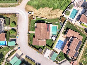 An aerial view of a residential area with multiple houses, a swimming pool, and a road.