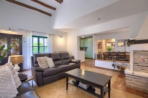 A spacious living area with a leather sofa, a coffee table, and a dining area with a fireplace.